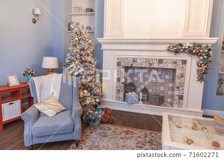 Classic Christmas decorated interior room, New year tree with silver decorations. Modern blue classical style interior design apartment with fireplace and armchair. Christmas eve at home. 71602271