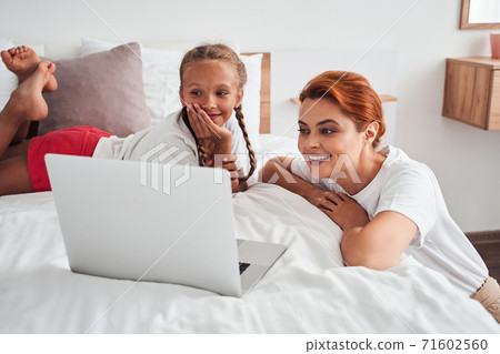 Mom and daughter watching a cartoon Mom and daughter watching a cartoon 71602560