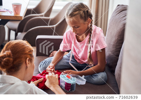 Mother sewing dolls with her children Mother sewing dolls with her children 71602639