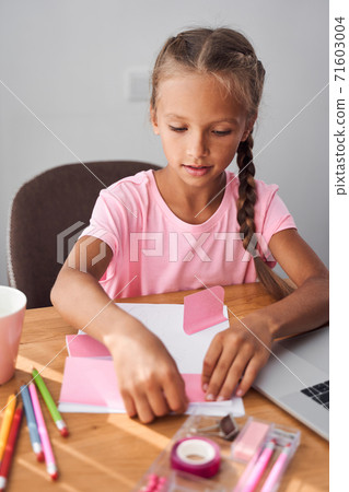 Kid pasting stickers on paper 71603004