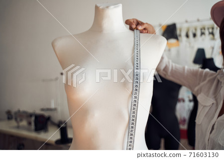 Girl measuring mannequin in studio Girl measuring mannequin in studio 71603130