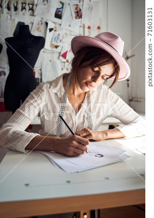 Dressmaker pondering on samples of trendy clothes Dressmaker pondering on samples of trendy clothes 71603131