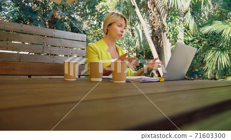 workaholic woman working on laptop in cafe outdoors with three cups of coffee 71603300