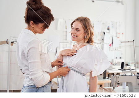 Designer measuring woman client's waist Designer measuring woman client's waist 71603528