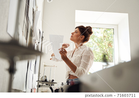 Woman contemplating sketches Woman contemplating sketches 71603711