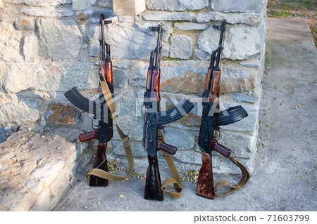 Kalashnikov AKMs near a stone wall 71603799