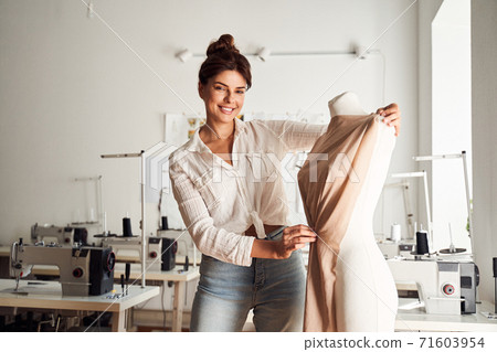 Dressmaker attaching fabric to mannequin Dressmaker attaching fabric to mannequin 71603954