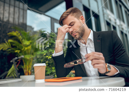 Handsome young businessman in black suit looking tired Handsome young businessman in black suit looking tired 71604219