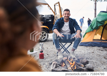 Friends sitting near bonfire Friends sitting near bonfire 71604780