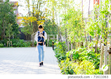 A woman is walking with her baby on a leash A woman is walking with her baby on a leash 71611063