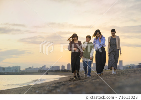 Four women walking along the sea in the dusk Four women walking along the sea in the dusk 71613028