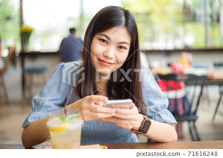 Beautiful asian women typing text on smartphone Beautiful asian women typing text on smartphone 71616248