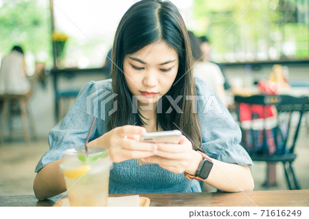 Beautiful asian women typing text on smartphone Beautiful asian women typing text on smartphone 71616249