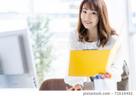 繁忙的商業女人在中間做著文書工作（看著相機） 71616482