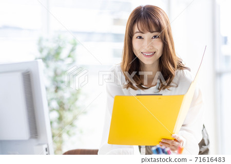 Busy business woman doing desk work in the middle (looking at the camera) 71616483