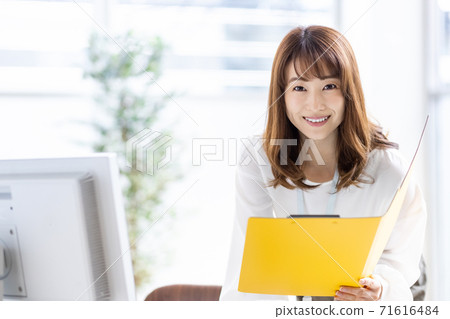Busy business woman doing desk work in the middle (looking at the camera) 71616484