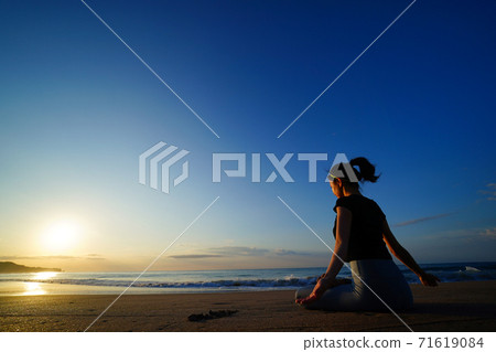 做在海灘的婦女瑜伽與朝陽在背景中 做在海灘的婦女瑜伽與朝陽在背景中 71619084