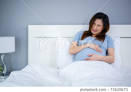 pregnant woman has a stomachache on bed 71620673