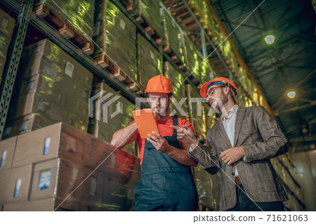 Warehouse worker and manager checking the data online and looking serious 71621063