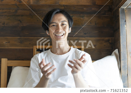 A young man in a white T-shirt talking looking at the camera A young man in a white T-shirt talking looking at the camera 71621352