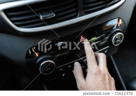 Interior view of a modern new car. Car driver pushing the attention alarm button. 71622370