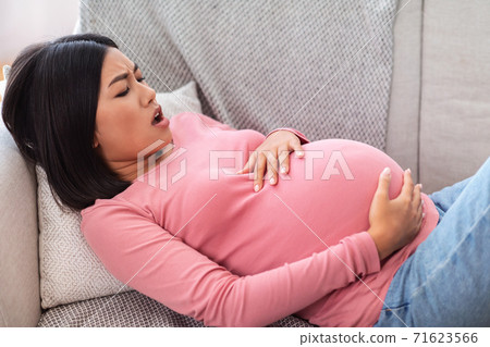 Pregnant Asian Woman Touching Belly Having Painful Contractions At Home Pregnant Asian Woman Touching Belly Having Painful Contractions At Home 71623566