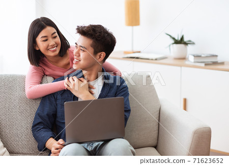 Asian Couple Using Laptop Browsing Internet Sitting In Living Room Asian Couple Using Laptop Browsing Internet Sitting In Living Room 71623652