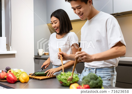 Asian Couple Cooks In Modern Kitchen, Laughing During Dinner Preparartion Asian Couple Cooks In Modern Kitchen, Laughing During Dinner Preparartion 71623658
