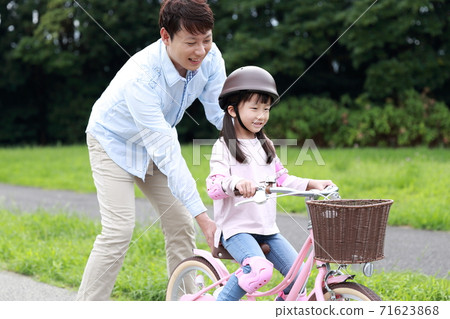 Parents and children practicing by taking training wheels on their bicycles 71623868