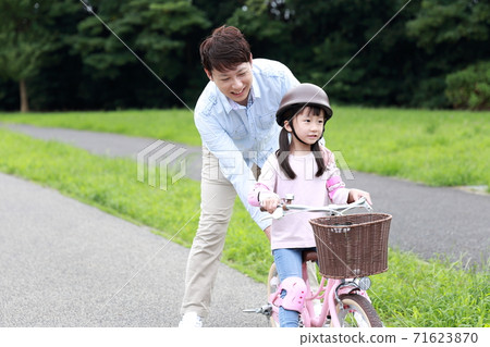 Parents and children practicing by taking training wheels on their bicycles 71623870