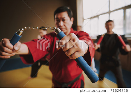 Japanese man shows nunchucks to the camera. Japanese man shows nunchucks to the camera. 71624826