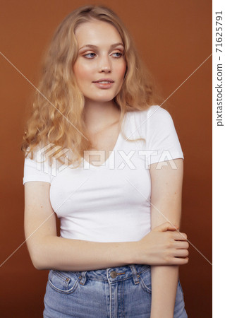 young pretty girl with blond curly hair posing cheerful on brown background, lifestyle people concept 71625791