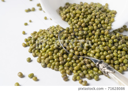 Heap of green mung beans in a white ceramic bowl on a white table close-up Heap of green mung beans in a white ceramic bowl on a white table close-up 71628086