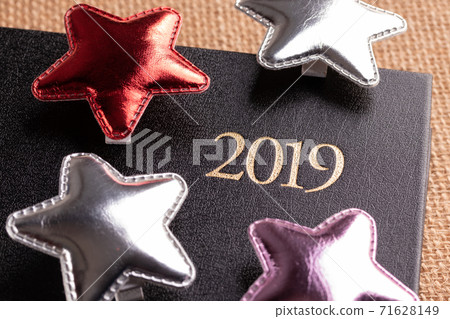 Closed black notebook with holiday decorations with the inscription 2019 for doing business and writing wishes for the year Closed black notebook with holiday decorations with the inscription 2019 for doing business and writing wishes for the year 71628149