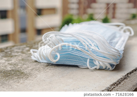 Medical protective surgical masks on an old concrete windowsill against the background of the buildings of a city street. The concept of unhygienic use of protective equipment against coronavirus Medical protective surgical masks on an old concrete windowsill against the background of the buildings of a city street. The concept of unhygienic use of protective equipment against coronavirus 71628166