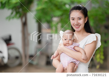 Beautiful Asian mother holding her infant portrait smiling looking camera. Beautiful Asian mother holding her infant portrait smiling looking camera. 71630121
