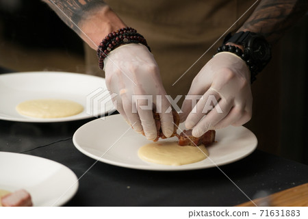 Closeup of chief serving delicious roasted pork meat wrapped in bacon. Irish traditional dish wrapped pork loin with roasted garlic Closeup of chief serving delicious roasted pork meat wrapped in bacon. Irish traditional dish wrapped pork loin with roasted garlic 71631883