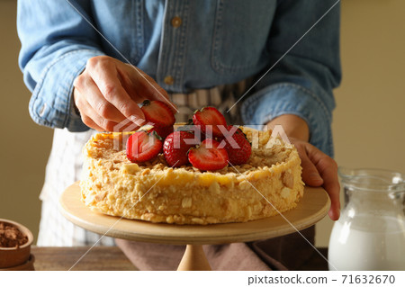 Woman puts strawberries on delicious Napoleon cake Woman puts strawberries on delicious Napoleon cake 71632670