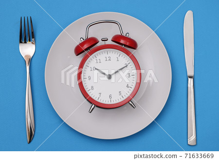 There is a red alarm clock on white plate There is a red alarm clock on white plate 71633669