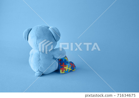 World Autism Awareness day, concept with teddy bear holding puzzle or jigsaw pattern on heart World Autism Awareness day, concept with teddy bear holding puzzle or jigsaw pattern on heart 71634675