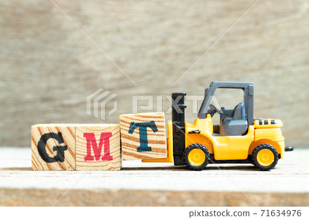 Toy forklift hold letter block T to complete word GMT (abbreviation of Greenwich Mean Time) on wood background Toy forklift hold letter block T to complete word GMT (abbreviation of Greenwich Mean Time) on wood background 71634976