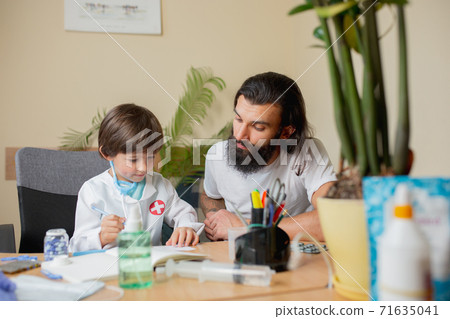 Little boy playing pretends like doctor examining a man in comfortabe medical office 71635041