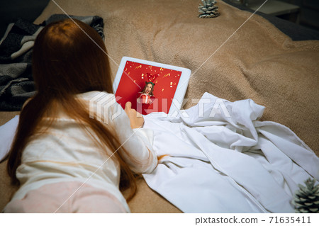 Happy caucasian little girl during video call or messaging with Santa using laptop and home devices, looks delighted and happy Happy caucasian little girl during video call or messaging with Santa using laptop and home devices, looks delighted and happy 71635411