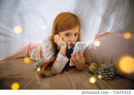 Happy caucasian little girl during video call or messaging with Santa using laptop and home devices, looks delighted and happy Happy caucasian little girl during video call or messaging with Santa using laptop and home devices, looks delighted and happy 71635418