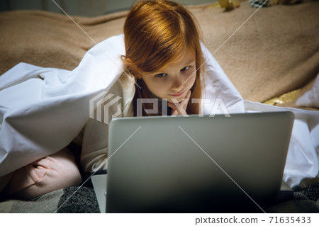 Happy caucasian little girl during video call or messaging with Santa using laptop and home devices, looks delighted and happy 71635433