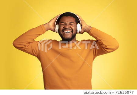Young african-american man's portrait isolated on yellow studio background, facial expression. Beautiful male half-lenght portrait with copyspace. Young african-american man's portrait isolated on yellow studio background, facial expression. Beautiful male half-lenght portrait with copyspace. 71636077