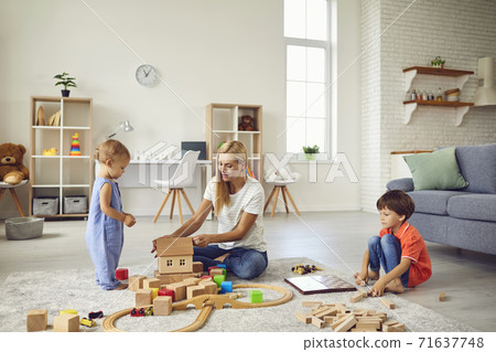 Mother playing educational games with smiling children on floor at home Mother playing educational games with smiling children on floor at home 71637748