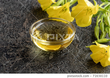 A bottle of evening primrose oil with fresh evening primrose flowers 71638110