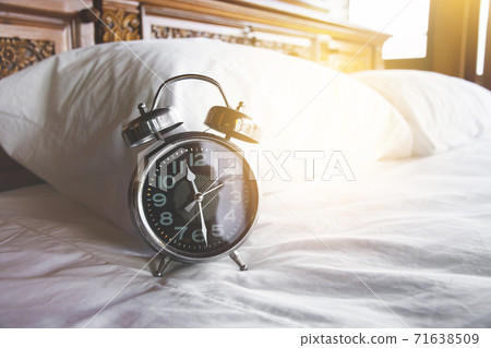 Vintage alarm clock on bed in bedroom at 11:28 am. Vintage alarm clock on bed in bedroom at 11:28 am. 71638509