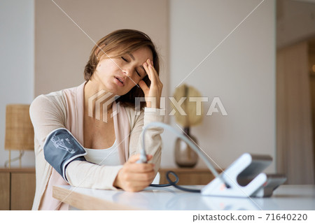 Pregnant woman measures blood pressure with an electronic tonometer. neuralgia during pregnancy 71640220